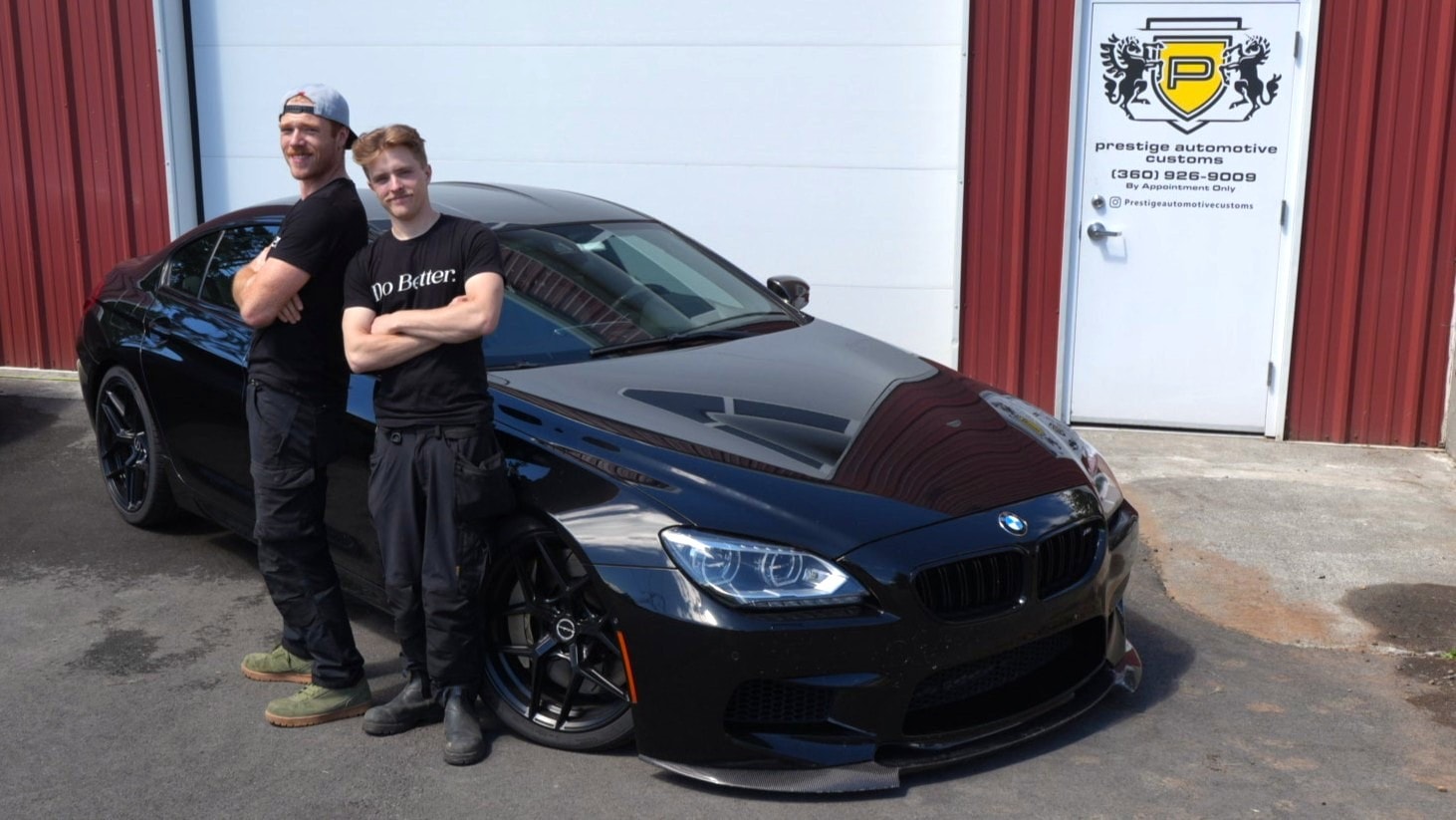The Prestige Automotive Customs team with a blacked-out BMW M6 Gran Coupe outside the Monroe shop